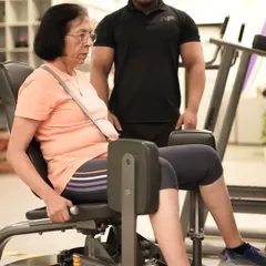 Fitness is for everyone, at any age. Here, one of our expert trainers provides personalized guidance to a member, ensuring her form is safe and effective on the hip adductor machine.