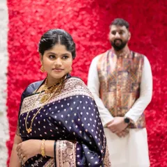 A candid shot showing her elegant side profile. The soft makeup highlights her features beautifully against the vibrant red background.