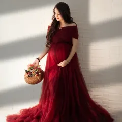 The beauty of natural light. Here, the sunlight streaming through the window creates a soft, warm glow on this mom-to-be in a rich, deep red tulle gown.