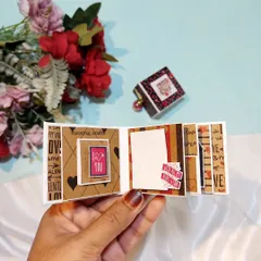 An open view of a tiny accordion-style scrapbook. It unfolds to reveal a sequence of small photos and decorative elements.