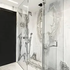 Luxury is in the details. For this executive bathroom, we used bookmatched Satvario Gold stone slabs to create a seamless, dramatic pattern in the shower enclosure. This technique turns natural stone into a work of art, demonstrating our commitment to high-end materials and meticulous craftsmanship in bathroom design.