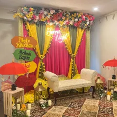 We love adding fun, personal touches to your Mehndi night. This cozy setup features a custom neon sign and a quirky "Photo Khichao, Mehndi Lagao" signboard, creating a perfect, Instagrammable corner for guests to enjoy.
