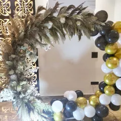 A modern and rustic-chic backdrop combining two popular styles. We created an arch using dried pampas grass and florals, paired with a partial balloon garland in a classic black, white, and gold color scheme.