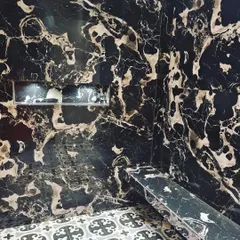 A shower designed with a built-in bench and niche, using dramatic black and gold marble. This is a perfect example of how to combine luxury with practical comfort.