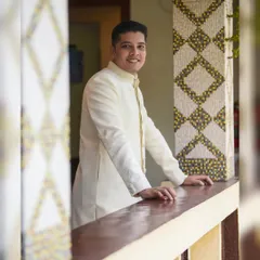 A friendly and approachable portrait of the groom. His warm smile and relaxed posture on the balcony give this photo a welcoming and happy feel.