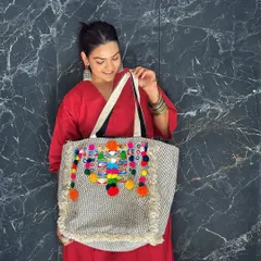 I love playing with color, and this tote bag is all about celebrating vibrant Indian crafts. The combination of intricate mirror work and playful, multi-colored pom-poms makes it a joyful statement piece that adds instant energy to a simple ethnic outfit.