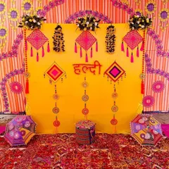 This is a classic Haldi ceremony backdrop I created, filled with traditional elements. The vibrant yellow cloth is decorated with colorful tassels and Rajasthani-style umbrellas, creating a festive and picture-perfect setting for your home function.