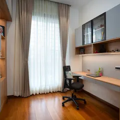 This view highlights the floating desk and overhead storage. The warm wood tones contrast beautifully with the grey accent wall, and natural light floods in from the large window.