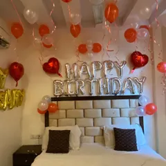 Here is a classic birthday bedroom setup. I used silver 'Happy Birthday' foil balloons as the centerpiece above the bed, complemented by red, orange, and white balloons on the ceiling for a cheerful and celebratory atmosphere.