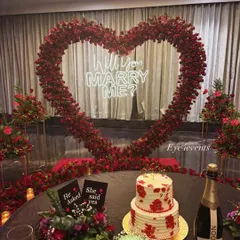 A complete romantic scene set for a "yes". We paired the grand red rose heart arch with a beautifully set table featuring champagne, cakes, and floral arrangements for a post-proposal celebration.