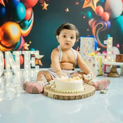 A look of surprise after the first smash. The colorful balloon backdrop and festive props create a perfect party atmosphere for this 'ONE-derland' theme.