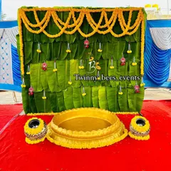 A classic South Indian decoration featuring a backdrop made of fresh banana leaves. We adorned it with marigold flower garlands (chendu hoovu) and hanging floral strings for a simple, natural, and traditional look.
