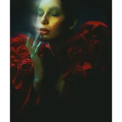An artistic, dreamlike portrait of 'Athena'. I used a slow shutter speed and colored gels to paint with light, creating a soft, ethereal glow around the model's face as she interacts with the red floral styling.