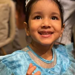 A beautiful little princess in her sparkling blue dress and tiara, smiling with pure joy. It's wonderful to see kids transform into their favorite characters.