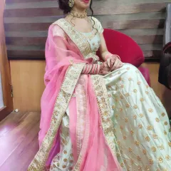 This side view of the pista green lehenga highlights the vibrant peach dupatta and the detailed gold embroidery along its border.