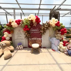 I create beautiful and memorable setups for milestones like baby showers. This 'Over the Moon' theme includes a custom backdrop, an elegant balloon arch in earthy tones, and adorable props like teddy bears and a wicker peacock chair for the mom-to-be.