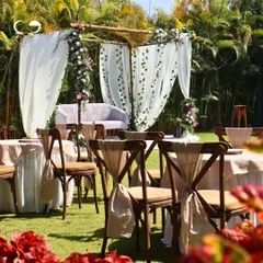 We created a dreamy, rustic setting for an outdoor Roka ceremony. A simple wooden frame draped with flowing white curtains and adorned with floral arrangements provides a beautiful, natural backdrop for the couple.