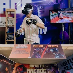 Ready to box in the virtual ring! This player is using VR boxing gloves for a more realistic and active gaming session. The spectator screen behind him shows his opponent.