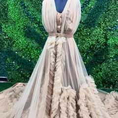 This beige designer gown features beautiful ruffles and a flowing train. It's a unique and elegant option available for rent from my collection.