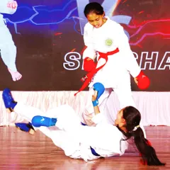 A decisive moment in a Kumite demonstration. One student executes a controlled sweep, showcasing the practical application of techniques learned in the dojo.