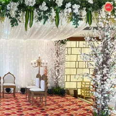 This angle of the white mandap highlights the beautiful textures, from the patterned carpet to the delicate blossoms and the soft glow of the fairy light curtain.