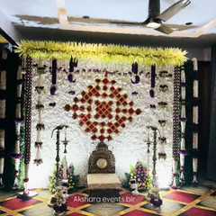 A close-up of a Haldi or Sreemantham backdrop, showing the intricate geometric pattern made with red and white flowers. The decor is complemented by hanging floral tassels.