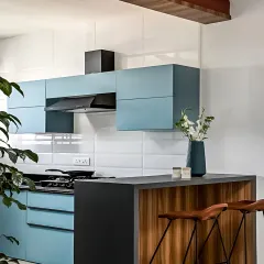 A contemporary kitchen design with a breakfast bar for casual dining. The combination of powder blue cabinets, a dark countertop, and wood accents creates a fresh and modern aesthetic.
