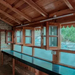 In the Sargakhet Handicraft Centre, we designed a cafeteria space that opens up to the stunning Mukteshwar valley. The long service counter is framed by traditional wooden windows with intricate carvings, blending new functionality with the building's historic character.