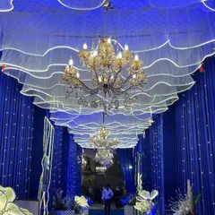 I believe the entrance sets the tone for the entire wedding. This is a grand walkway I designed, featuring royal blue drapes, elegant chandeliers, and a dreamy, wave-like ceiling with integrated lighting.