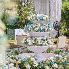 The centerpiece of the event was a magnificent three-tiered white fountain, overflowing with white chrysanthemums and blue-dyed carnations, creating a stunning floral spectacle.