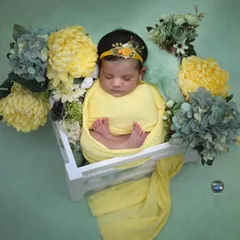 A burst of sunshine. This newborn is swaddled in bright yellow and surrounded by coordinating yellow and blue hydrangeas in a white wooden crate.