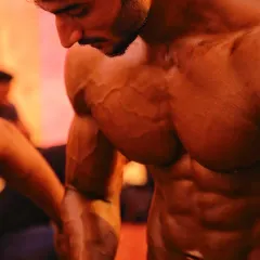 A close-up shot showing the vascularity and muscle fullness required for competition. This level of conditioning is achieved through a strict, personalized diet and training plan.