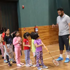 A group of young girls listens attentively as their coach explains a new drill, showcasing our structured group coaching for kids.