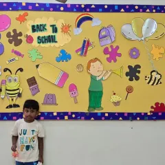A new student posing by the 'Back to School' board, ready to start his learning adventure with us.