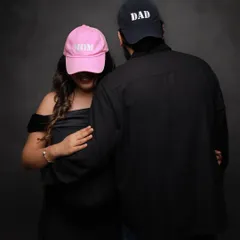 A fun and anonymous-style couple's portrait with "Mom" and "Dad" hats. This is a playful way to celebrate your new titles.