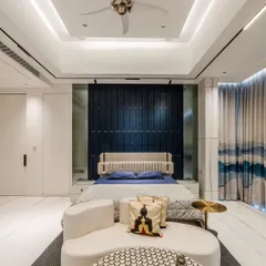 The deep blue 3D paneled accent wall serves as a dramatic backdrop for the bed. The layered ceiling with track lighting and the unique fan add to the room's modern and sophisticated character.