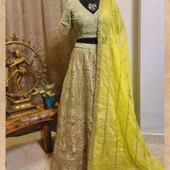 This gorgeous green lehenga is perfect for the wedding season. The net skirt is layered with delicate embroidery, and the matching blouse is paired with a contrasting bright yellow dupatta for a fresh, festive look.