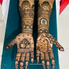 A stunning full-hand bridal mehendi featuring a beautiful Radha Krishna portrait on one palm and swan motifs with the couple's initials on the other. The arms are covered in detailed architectural and floral patterns.