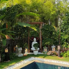 A serene Buddha statue creates a point of tranquil focus in this poolside Zen garden. We carefully selected white pebbles, stone lanterns, and lush bamboo to frame the setting, designing a space for quiet contemplation that harmonizes with the water.