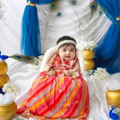 A happy little smile from our Janmashtami princess. The vibrant blues and whites of the backdrop make the entire scene feel so divine.