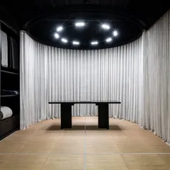 The gallery space in 'The Veiled Project' is organized as a carefully orchestrated movement. Two cylindrical pods, one displaying a bed and the other a work desk, anchor the design and guide the visitor's journey.