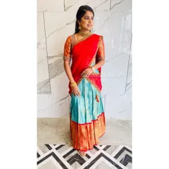A beautiful client glowing in a custom-designed half saree. We repurposed her traditional saree into this vibrant red and turquoise langa voni, perfect for wedding festivities. The rich colors and classic silhouette make it a timeless piece.
