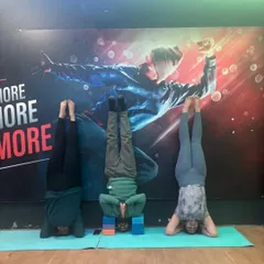 Headstand (Sirsasana) practice in the studio. Here, students use blocks for support to build confidence and ensure proper neck alignment, making the pose accessible and safe.