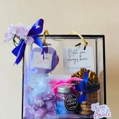 Holding up a finished bridesmaid hamper to show its convenient size and beautiful presentation. The purple theme is carried through from the ribbon to the items inside.