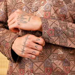 Royalty woven in every thread. A close-up on the sleeve of a brown patterned jacket, showing the intricate geometric embroidery.