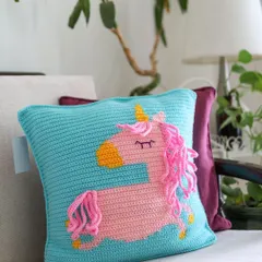 A happy Sunday moment with the Curly Tails Unicorn Cushion. The bright aqua blue pillow provides a perfect backdrop for the pink unicorn with its fun, curly mane and tail.