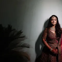 A full-length portrait of a bride at her reception, with her eyes closed in a moment of quiet reflection. The dramatic lighting adds to the elegance of the shot.