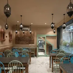 The dine-in space at Shiv Mishthan Bhandar features walls clad with lakhori bricks and traditional mouldings. Large glass panels create an interactive experience, connecting diners with the vibrant street life of Old Delhi.