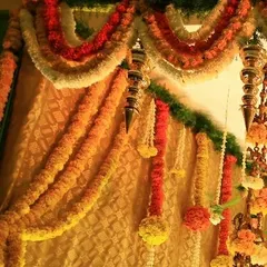A closer look at the dense floral backdrop. The vibrant colors of orange and yellow marigolds against a traditional gold brocade fabric create a look of pure opulence and celebration.