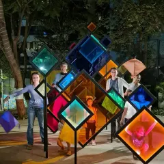 People interacting with the transformed 'Family Tree' installation, now adorned with colorful panels. The piece evolves with the seasons and festivals, reflecting the multicultural spirit of Mumbai.